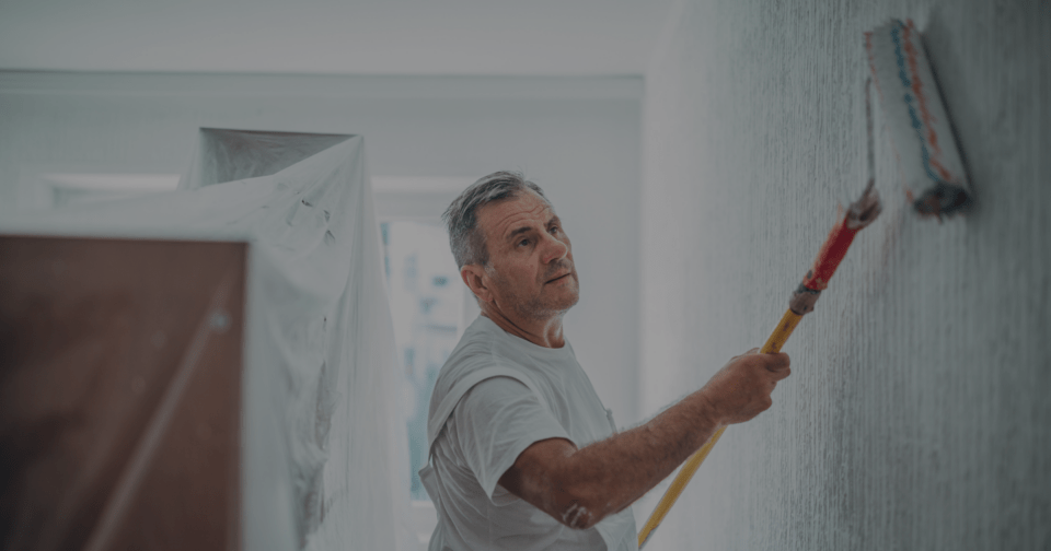 photo of a painter and decorator rolling paint onto an interior wall